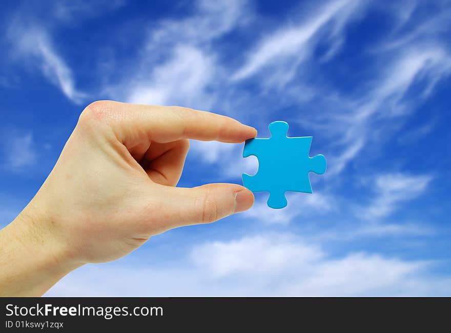 Puzzle in hand isolated on sky background