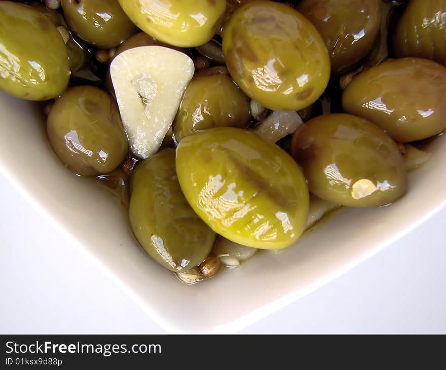 A white bowl full of delicious green olives