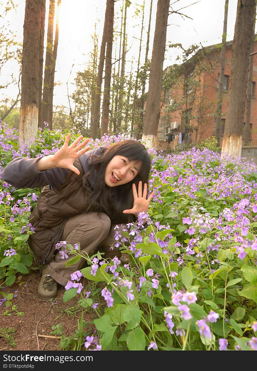 Chinese young girl squatting in the flowers