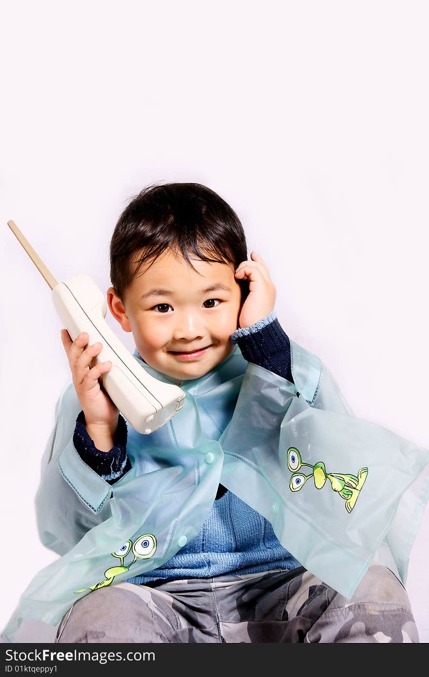 A picture of a little chinese boy holding a telephone in raincoat. A picture of a little chinese boy holding a telephone in raincoat