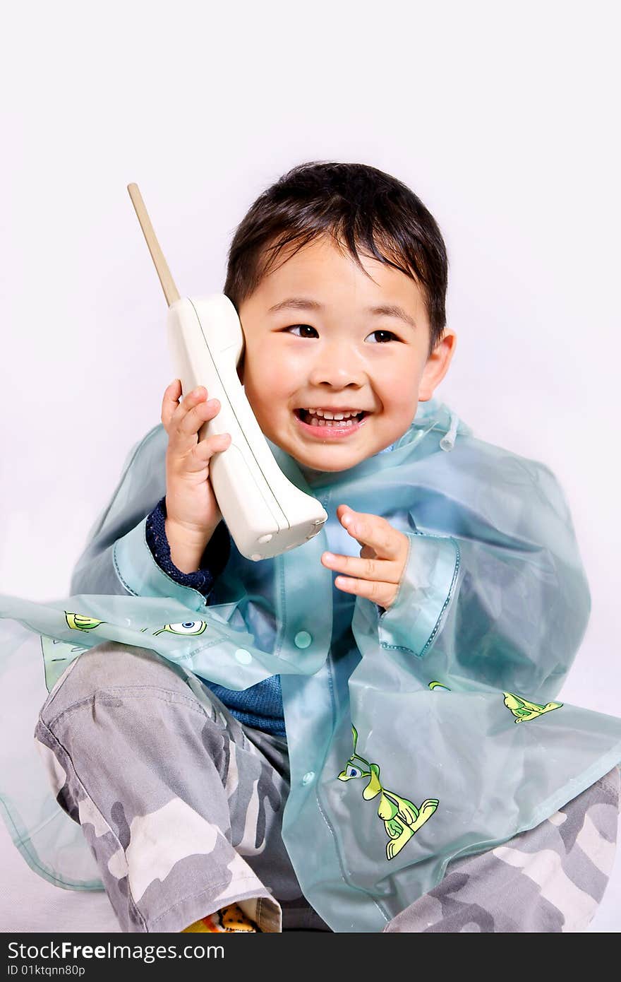 A picture of a little chinese boy holding a telephone in raincoat. A picture of a little chinese boy holding a telephone in raincoat