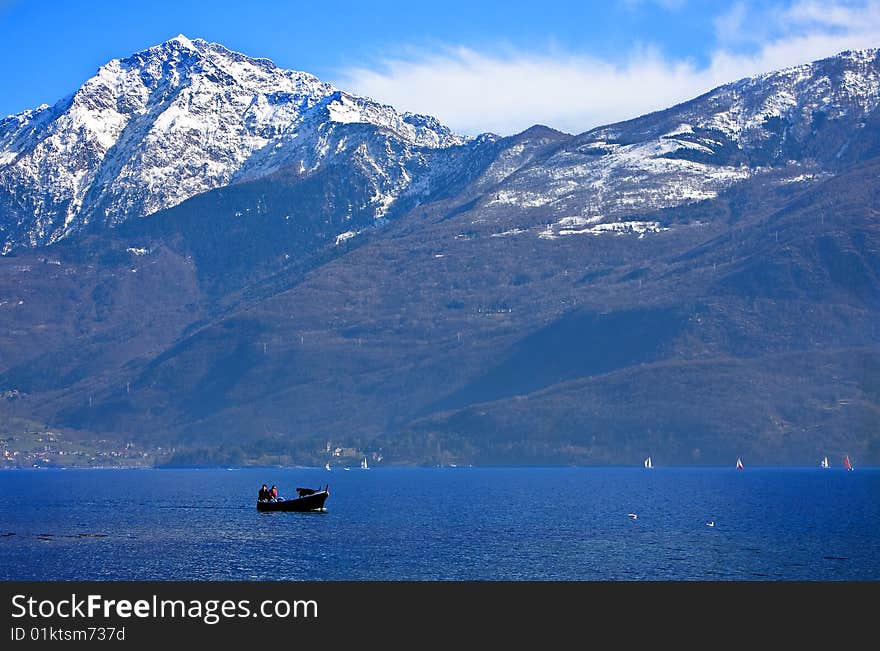 Lake by boat and snow-capped mountains