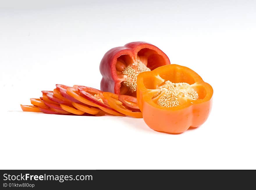 Cut orange and red sweet pepper showing seeds with slices on white. Cut orange and red sweet pepper showing seeds with slices on white