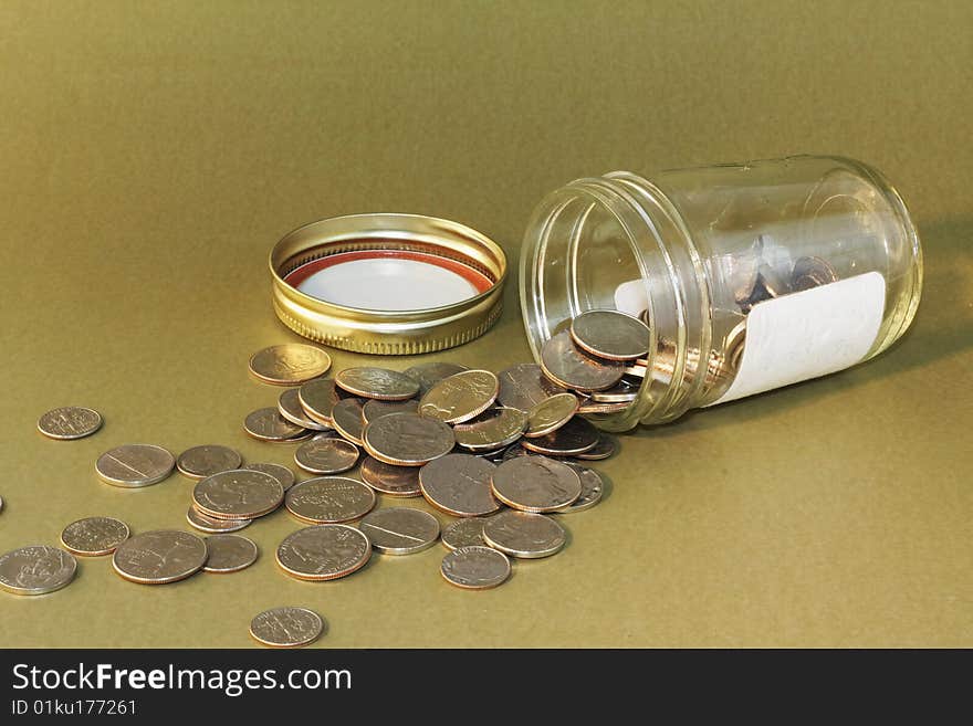 A jar of coins which appears to be knocked over spilling it's contents for access. A jar of coins which appears to be knocked over spilling it's contents for access