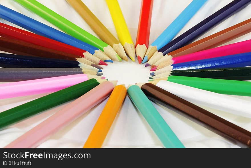 A circle of colored pencils forming a pinwheel of colors. A circle of colored pencils forming a pinwheel of colors