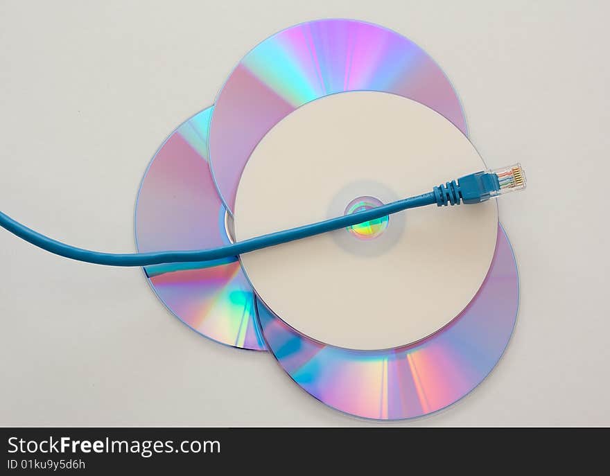 Blue Ethernet cable running over blank DVD or CD symbolizing data piracy. Blue Ethernet cable running over blank DVD or CD symbolizing data piracy