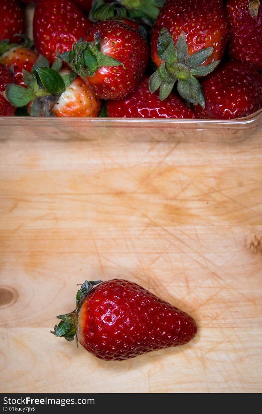 Whole strawberry singled out from a coffer on a cutting board. Whole strawberry singled out from a coffer on a cutting board.