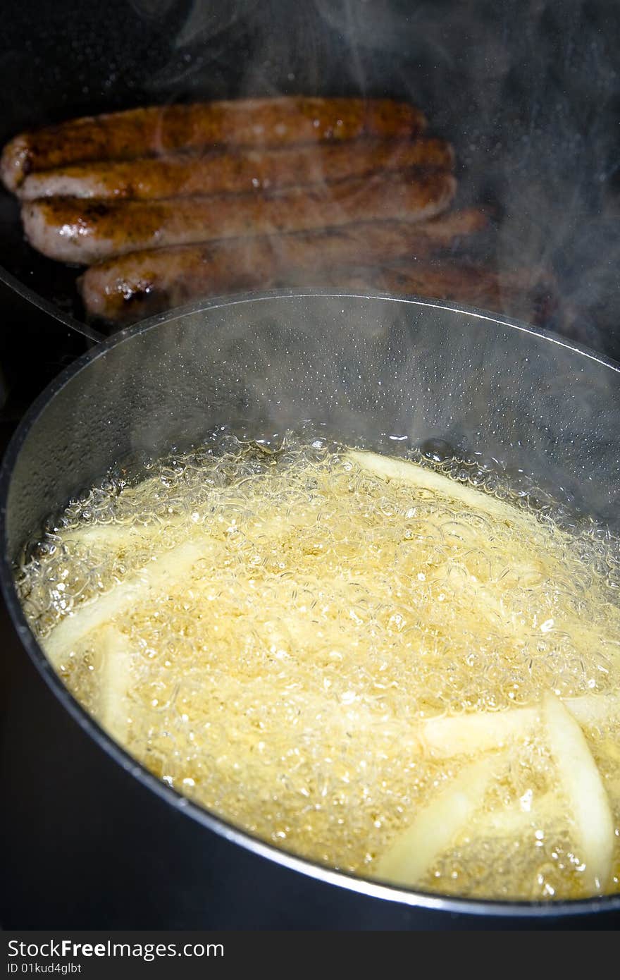 Image of French fries and sausages being prepared.