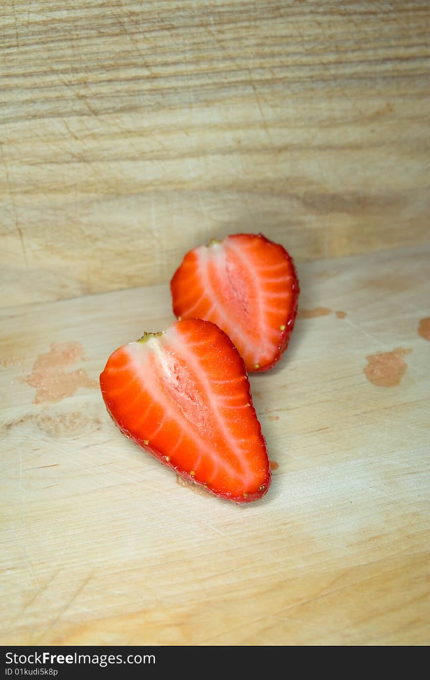 Two strawberry halves on a wooden cutting board. Two strawberry halves on a wooden cutting board.