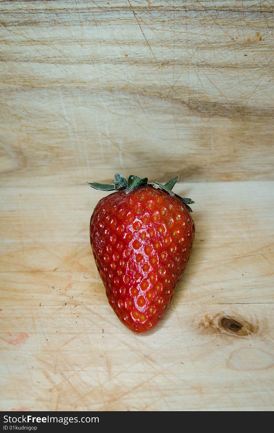 Macro image of a strawberry on a wooden cutting board. Macro image of a strawberry on a wooden cutting board.