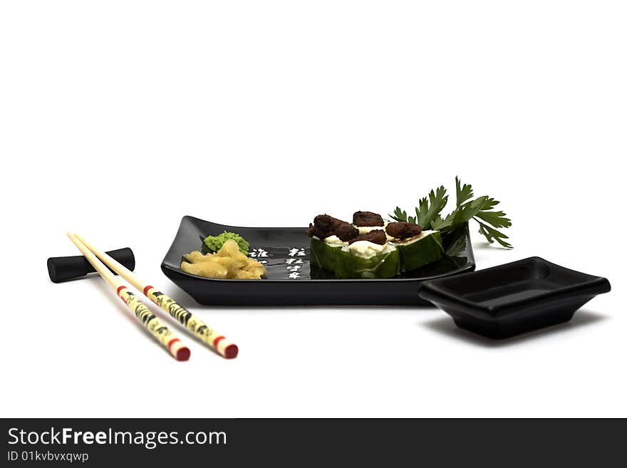 A set of sushi on a black plate with wasabi and gari, isolated on a white background, wish hashi ans soy sauce. A set of sushi on a black plate with wasabi and gari, isolated on a white background, wish hashi ans soy sauce.