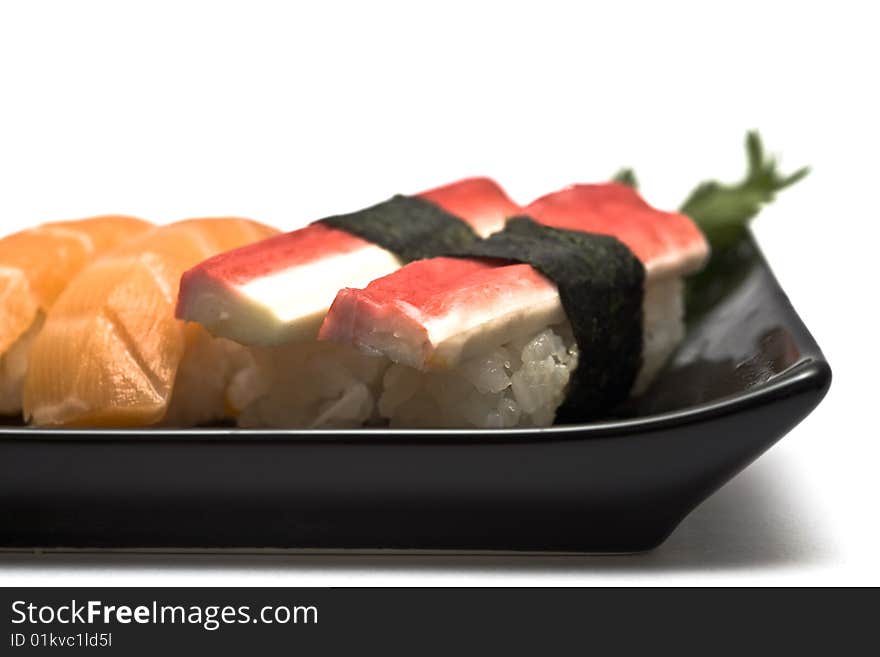 A set of sushi on a black plate with wasabi and gari, isolated on a white background, close-up. A set of sushi on a black plate with wasabi and gari, isolated on a white background, close-up.