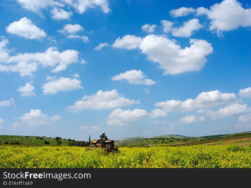 Tractor working at the  field under cloudy sky. Tractor working at the  field under cloudy sky