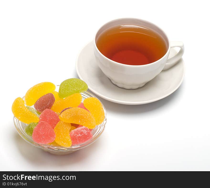 Fruit candy and tea cup. It is isolated on a white background