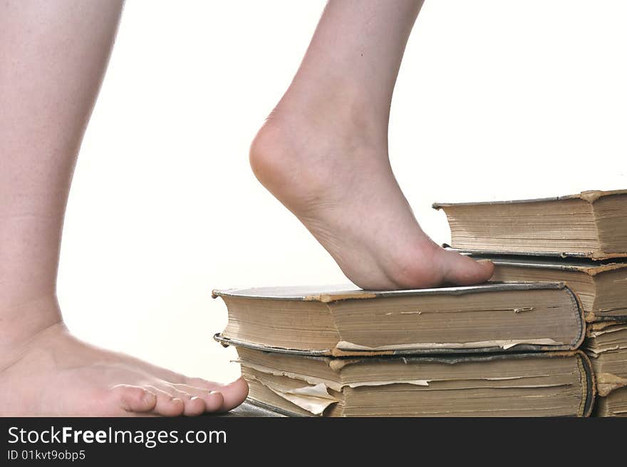 Girls feet stepping on stairway build from ancient books, isolated on white background. Girls feet stepping on stairway build from ancient books, isolated on white background