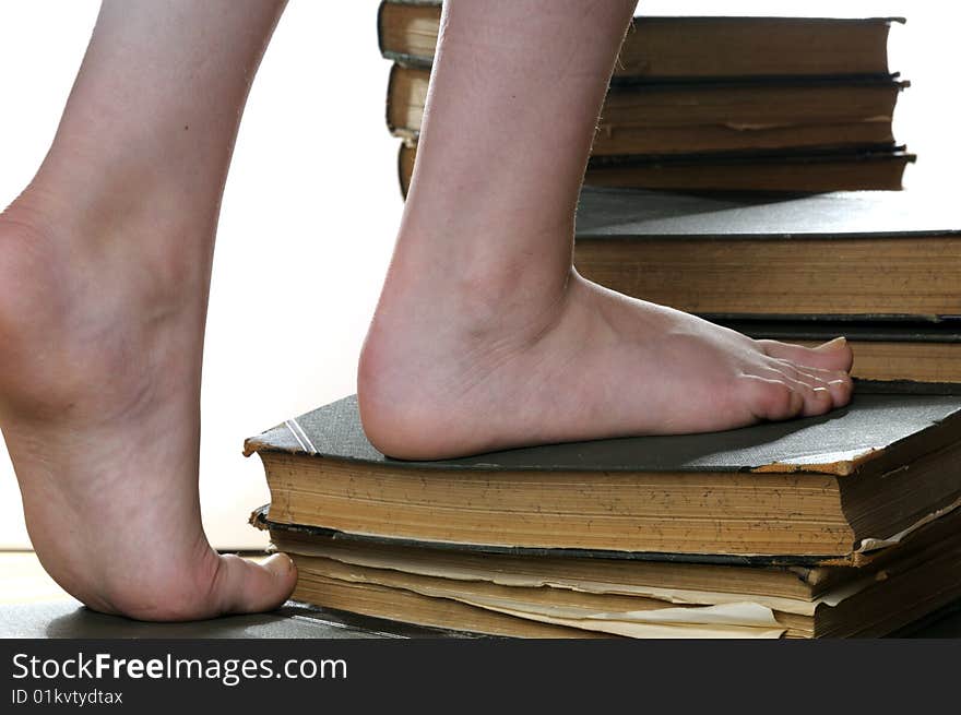 Girls feet stepping on stairway build from ancient books, isolated on white background. Girls feet stepping on stairway build from ancient books, isolated on white background