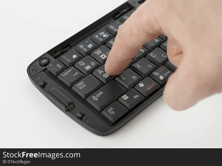 Finger pushing button on compact black keyboard. Finger pushing button on compact black keyboard