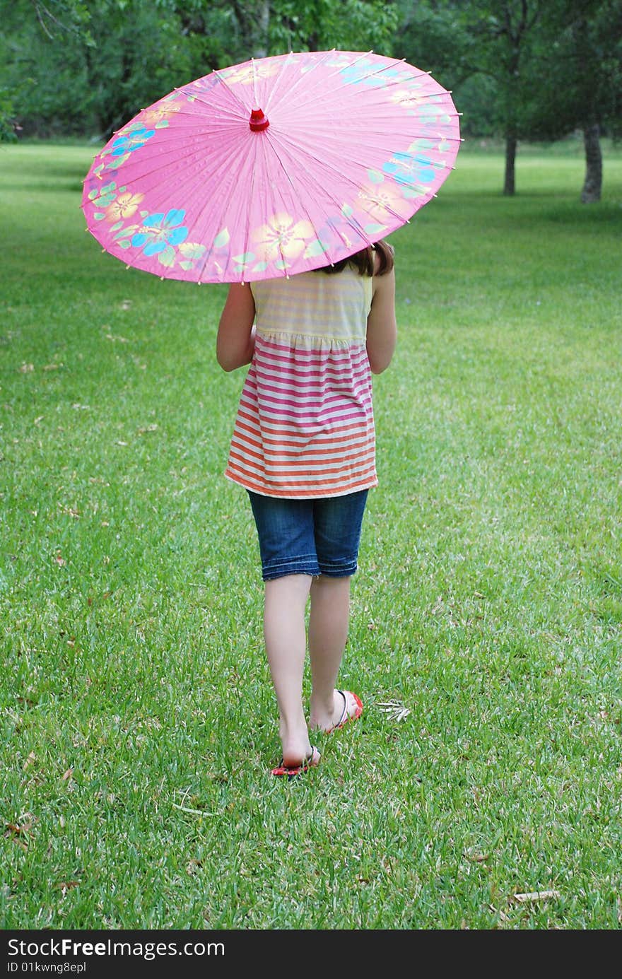 Beautiful 10 year old brown haired girl holding a parasol outdoors in the park. Beautiful 10 year old brown haired girl holding a parasol outdoors in the park