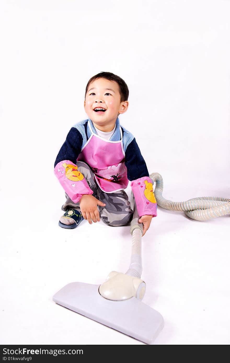 A picture of a little chinese boy playing with vacuum cleaner wearing apron. A picture of a little chinese boy playing with vacuum cleaner wearing apron