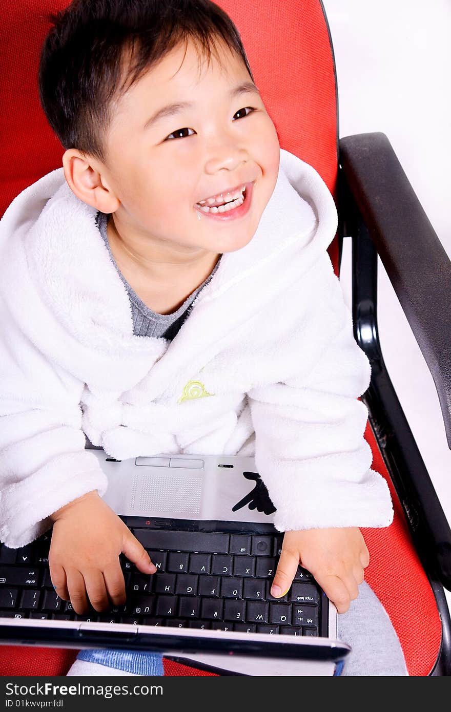 A picture of a little chinese boy playing with a notebook happily while wearing bathrobe. A picture of a little chinese boy playing with a notebook happily while wearing bathrobe