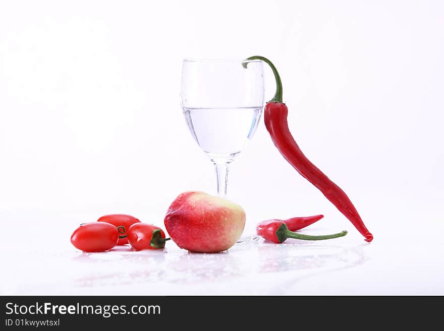 Peachs , peper and tomatoes on white background with goblet, water in it. Peachs , peper and tomatoes on white background with goblet, water in it