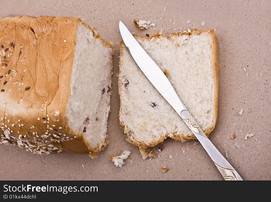 White background, bread in peieces, covered with til seed, cornmeal with knife on side. White background, bread in peieces, covered with til seed, cornmeal with knife on side