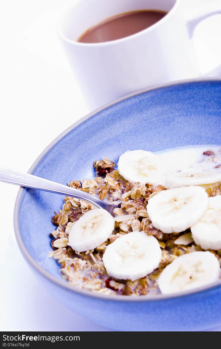 A blue bowl of muesli with bananas and a coffee. A blue bowl of muesli with bananas and a coffee