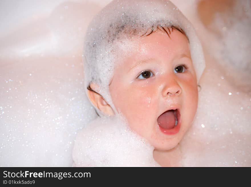 The little girl bathes in soapsuds