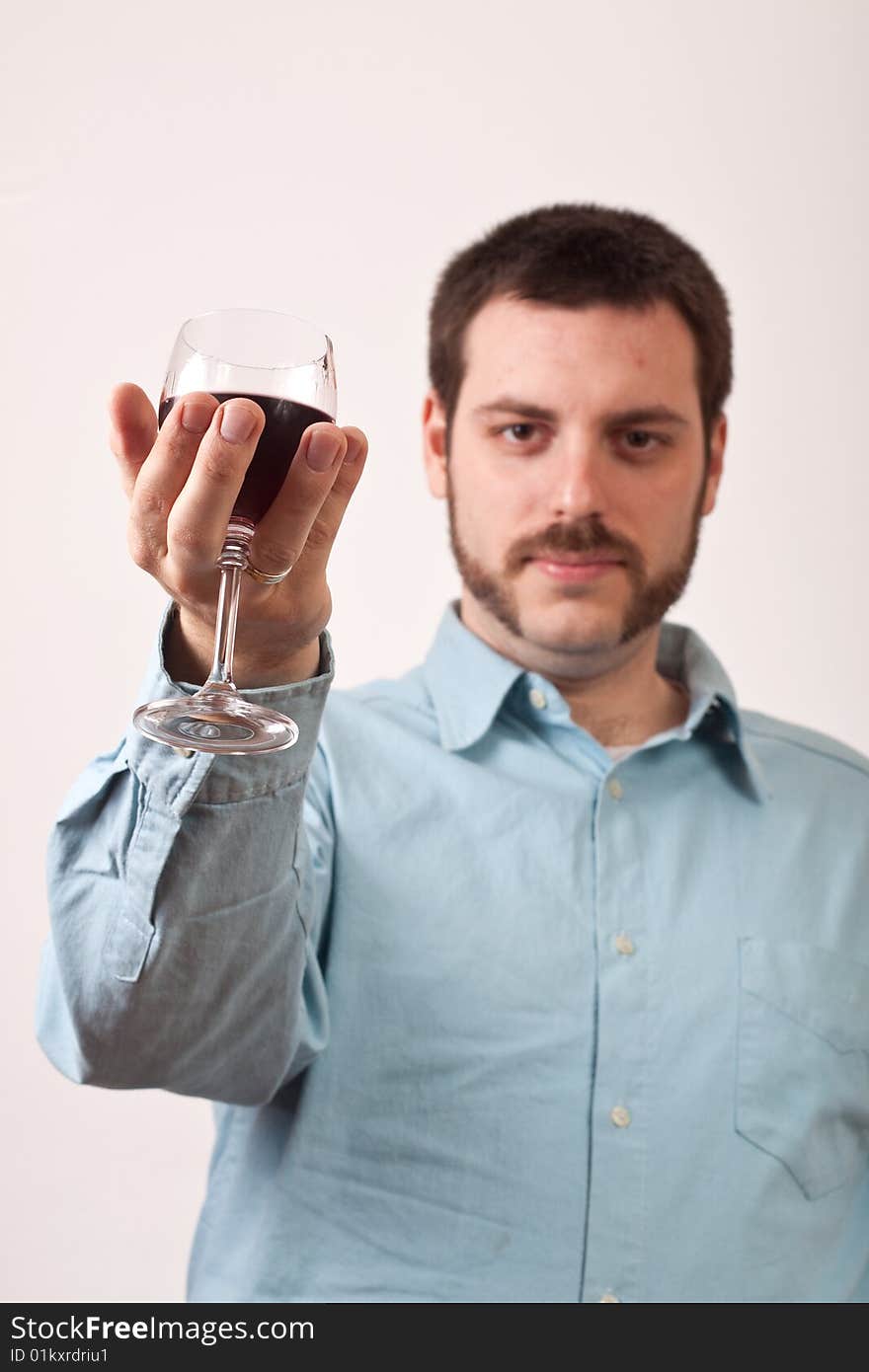 Young man holding a glass of red wine with focus on glass. Young man holding a glass of red wine with focus on glass