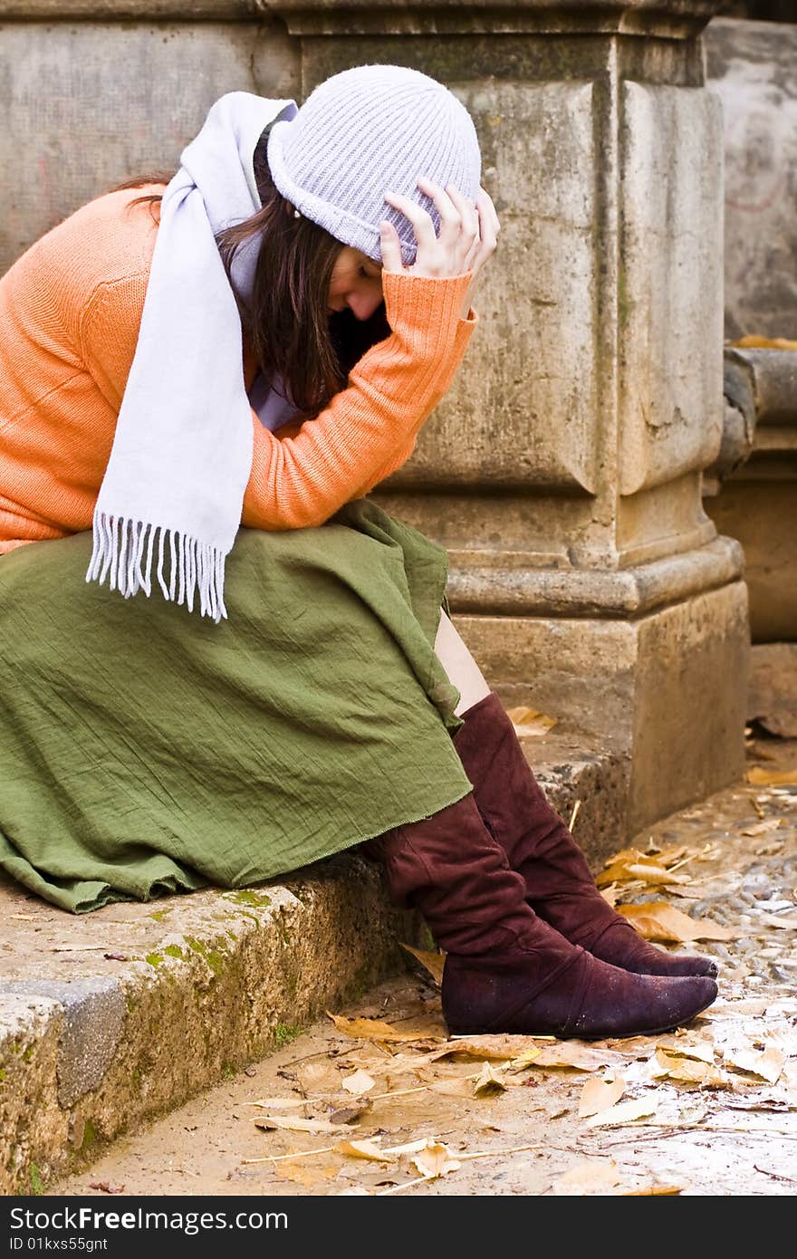 Young thoughtful woman sitting in stone stairs.