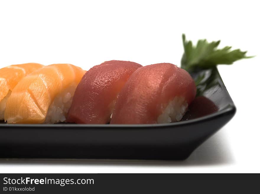 A set of sushi on a black plate with wasabi and gari, isolated on a white background, close-up. A set of sushi on a black plate with wasabi and gari, isolated on a white background, close-up.