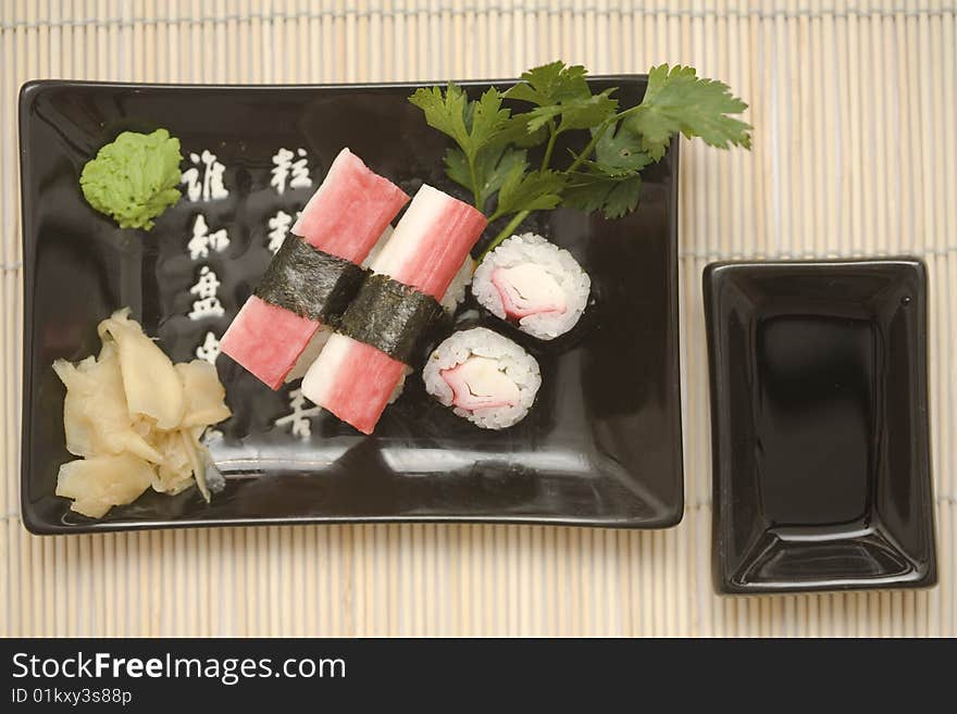 A set of sushi on a black plate with wasabi and gari, on a makisu (bamboo rolling mat). A set of sushi on a black plate with wasabi and gari, on a makisu (bamboo rolling mat).