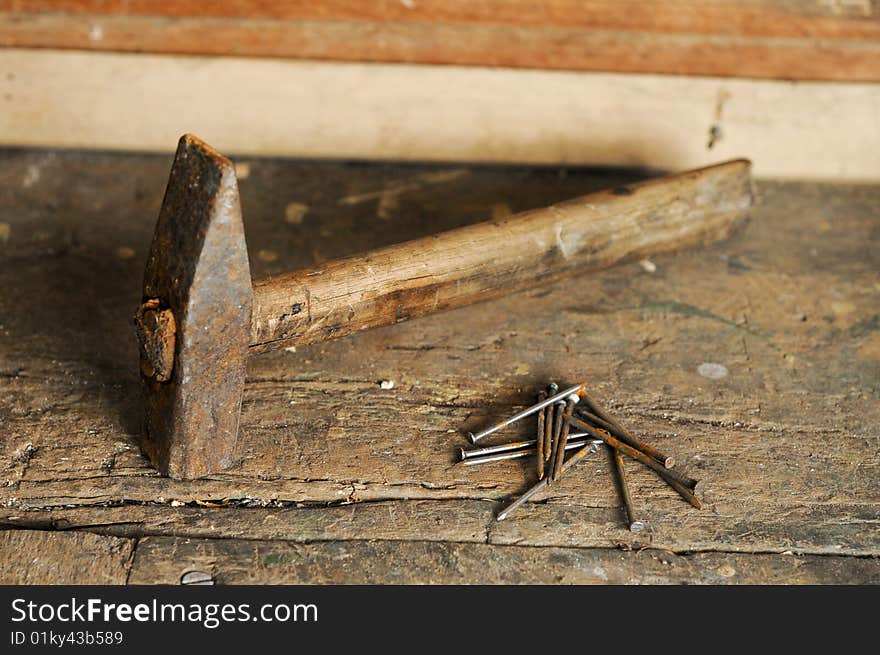 Old rusty hammer and nails on wooden table, focus on nails