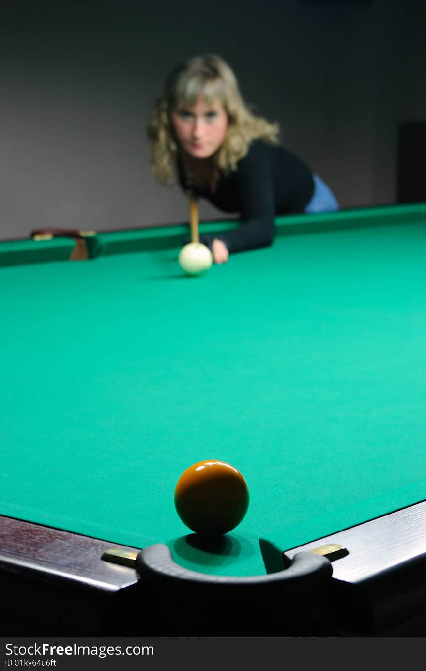 The girl beats a billiard sphere in a billiard pocket. The girl beats a billiard sphere in a billiard pocket