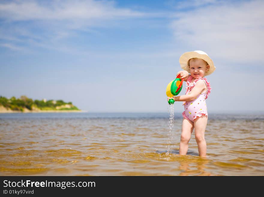 Small girl with watering-pot on the seashore. Small girl with watering-pot on the seashore