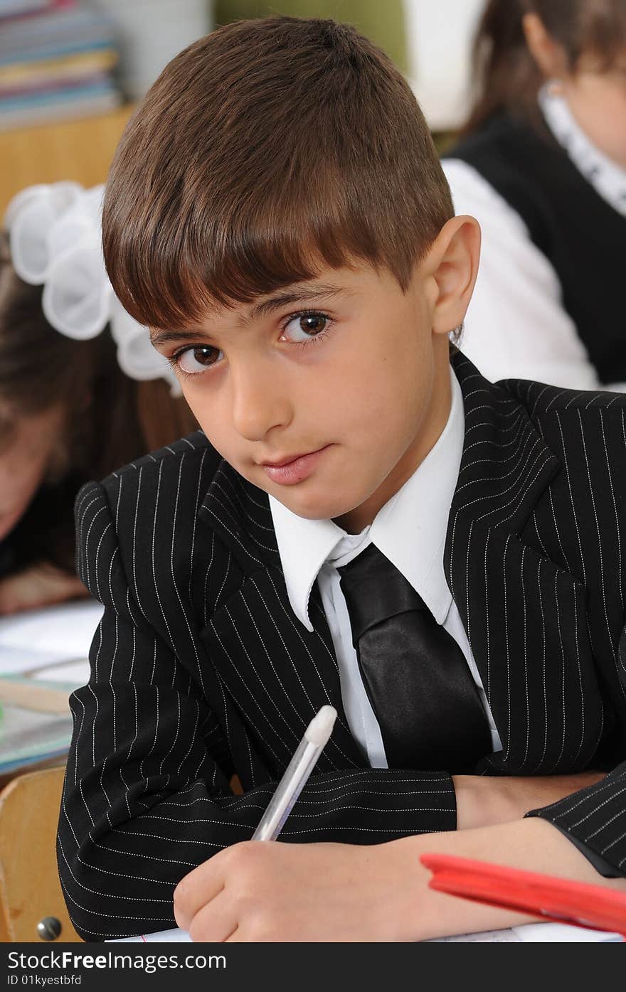 The boy the first-grader sits at a school school desk. The boy the first-grader sits at a school school desk.