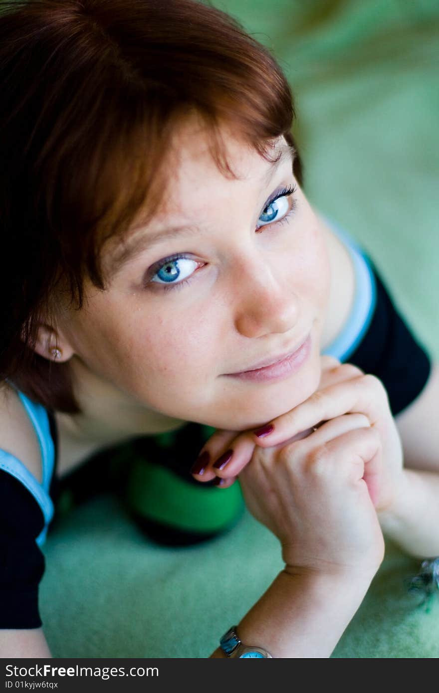 The girl looks expressive blue eyes, a blue T-shirt, hands folded. The girl looks expressive blue eyes, a blue T-shirt, hands folded