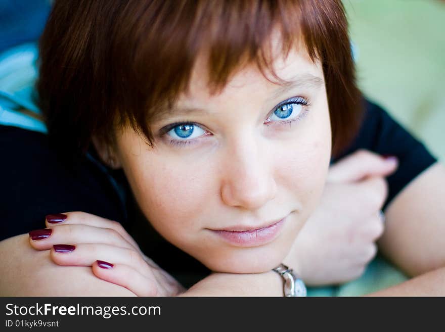 The girl looks expressive blue eyes, a blue T-shirt, hands folded. The girl looks expressive blue eyes, a blue T-shirt, hands folded