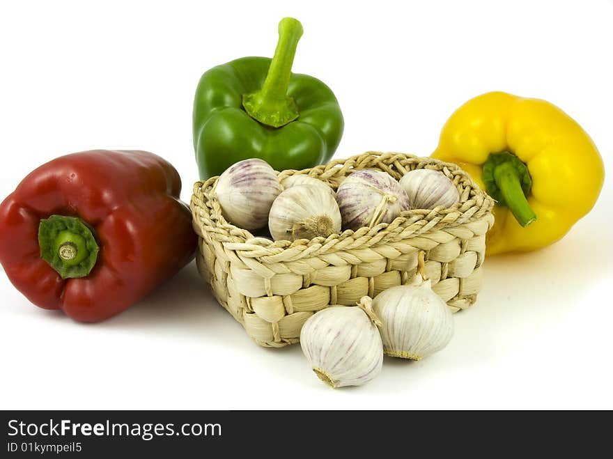 Three bell peppers and basket full of fresh garlics isolated on white background. Three bell peppers and basket full of fresh garlics isolated on white background