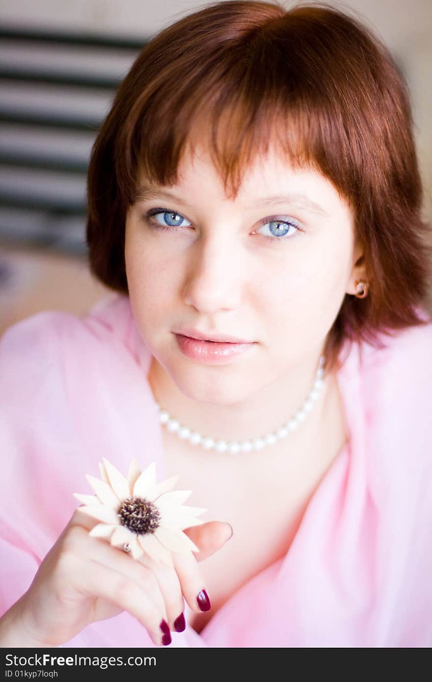 The girl looks expressive blue eyes, a pink dress, holds a flower in her hand. The girl looks expressive blue eyes, a pink dress, holds a flower in her hand