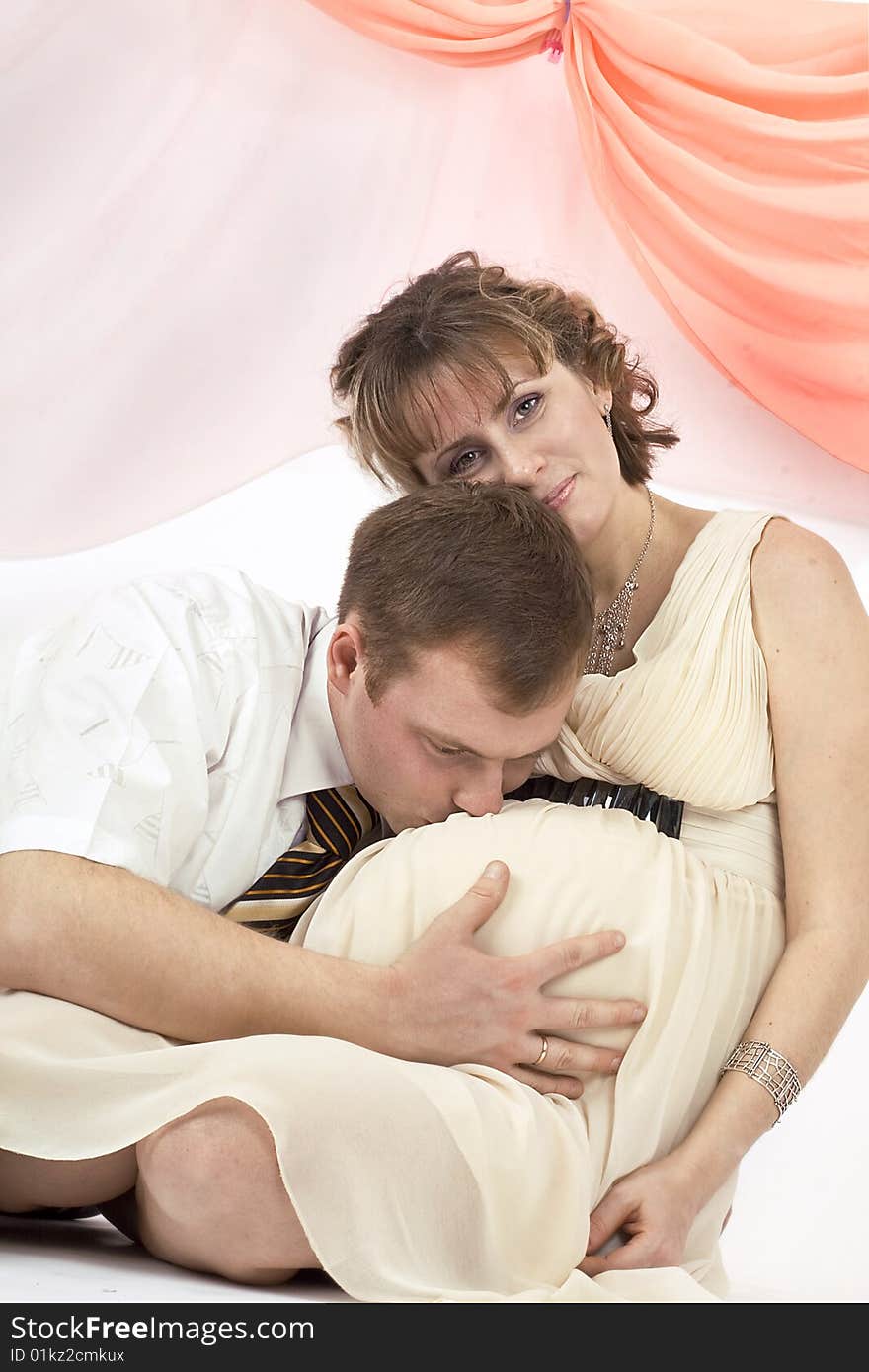 Young beautiful married couple the birth of the first child wait. Pink background. New photos every week