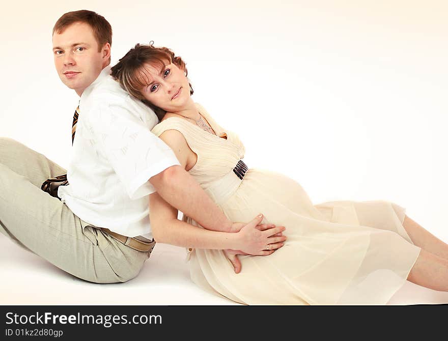 Young beautiful married couple the birth of the first child wait. Pink background. New photos every week