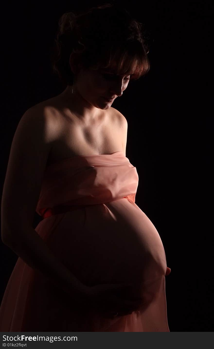 Portrait on black background the young beautiful woman waits for the child. New photos every week