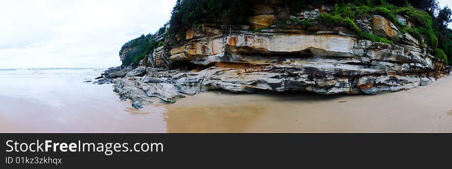 Panorama of a beach landscape with rocks and steps to beach houses