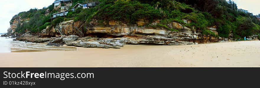 Panorama of a beach landscape with rocks and steps to beach houses