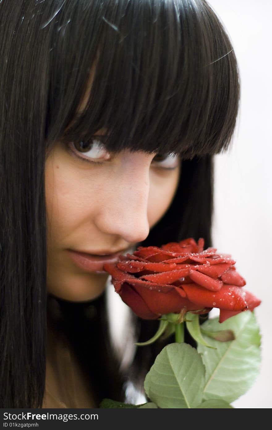 Girl sniffing beautiful flower - red rose. Girl sniffing beautiful flower - red rose