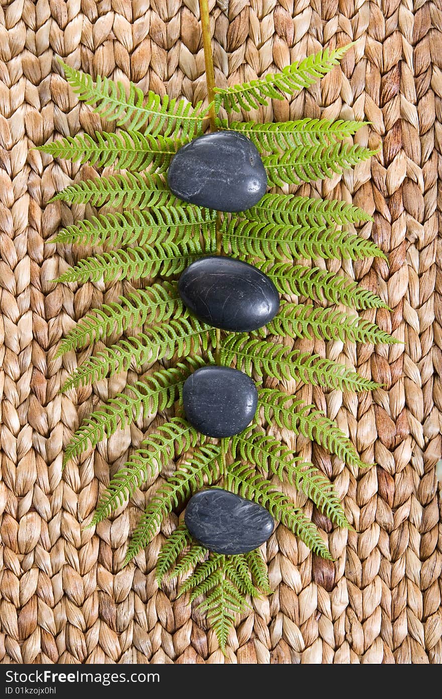 Zen Stones on a grass mat with a fern isolated on white