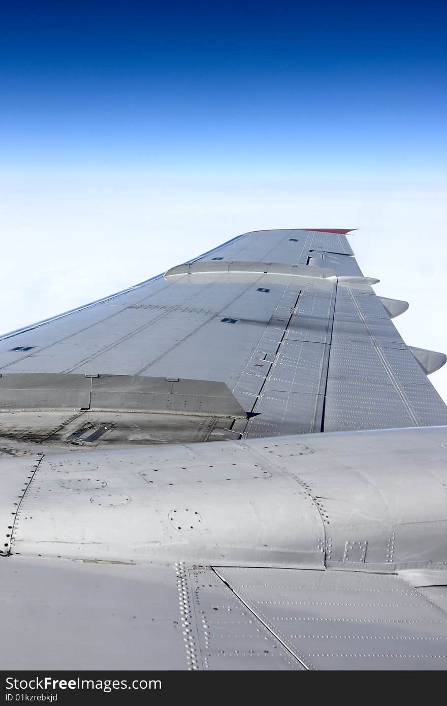 The silvery wing of a airliner in the sky. The silvery wing of a airliner in the sky