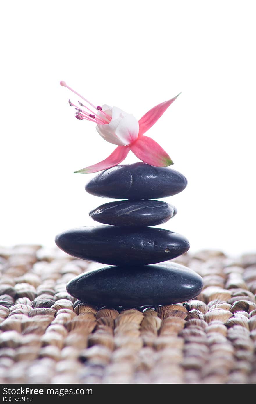 Zen stones with pink flowers on a grass matte