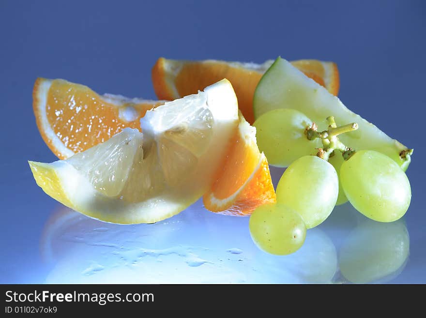 Various fruits lying on glassy blue background